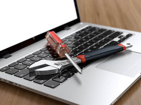 Image of a laptop with a wrench and screwdriver